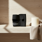 Adaptive intimacy thigh strap in black resting on a travertine stone shelf for mobility wellness.