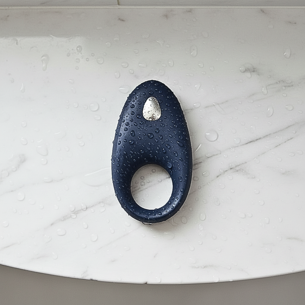 App-controlled constriction ring in blue silicone on a marble shower shelf with water droplets for a waterproof design.