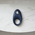 App-controlled constriction ring in blue silicone on a marble shower shelf with water droplets for a waterproof design.
