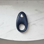 App-controlled constriction ring in blue silicone on a marble shower shelf with water droplets for a waterproof design.