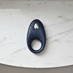 App-controlled constriction ring in blue silicone on a shelf with water droplets for a waterproof design.