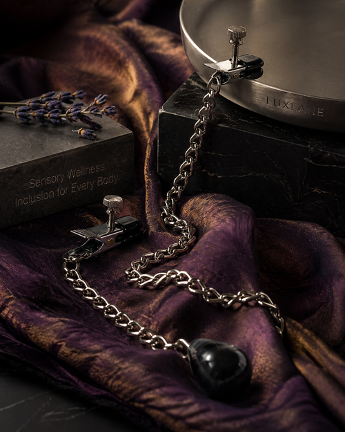 Close-up of a LUXLANE weighted sensory tool draped over raw amethyst silk and dark marble, featuring a 4.5 oz teardrop weight for gravity-assisted tactile feedback.