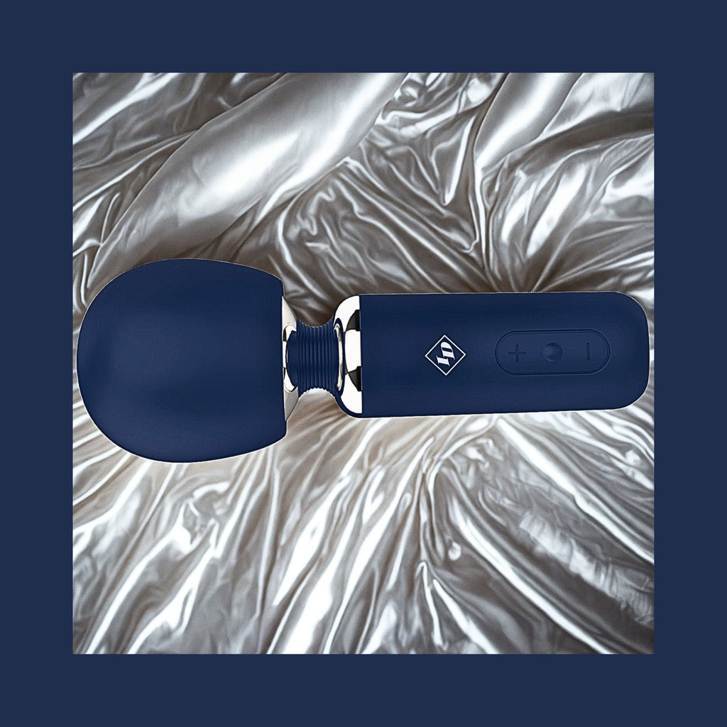 Give Into Me Wellness Wand for Flexible Percussive Care, shown on a luxury bedspread, highlighting its Ergonomic Stability Grip and flexible neck.