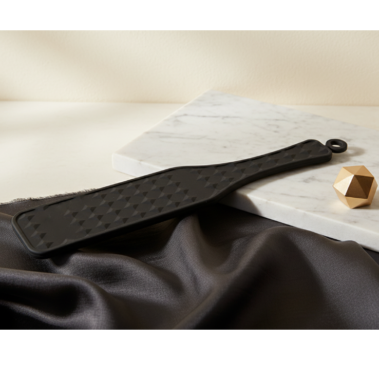 Matte black silicone sensory paddle with diamond texture on white marble — LuxLane tactile wellness tool