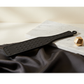 Matte black silicone sensory paddle with diamond texture on white marble — LuxLane tactile wellness tool