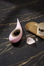 Precise external stimulation and pelvic wellness device in pink. Shown on black marble with luxury gold accents for sensory-friendly comfort.