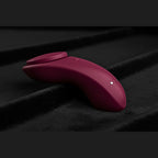 Red app controlled massager resting on luxury black felt used for neuro-inclusive sensory.